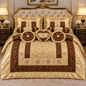 Luxury imported silk 9-piece comforter set in elegant gold and brown color combination featuring embroidered detailing, matching pillow covers, decorative cushions, neck rolls, and heart-shaped cushion displayed on a premium bedroom bed.